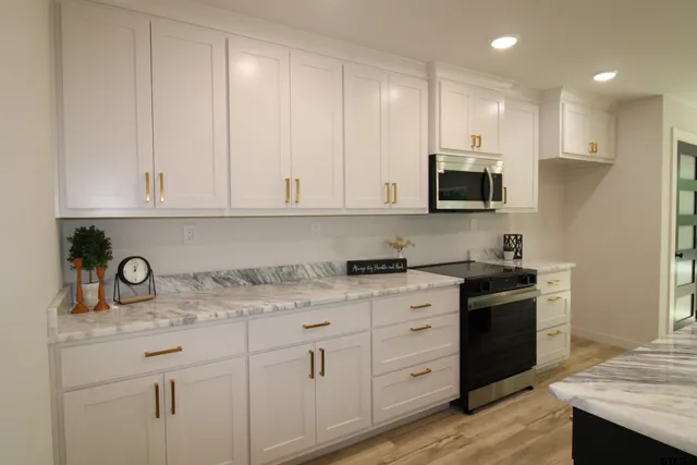a kitchen with stainless steel appliances granite countertop a stove a sink and white cabinets