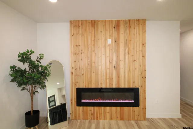 a view of hallway with paintings a potted plant and a wooden floor