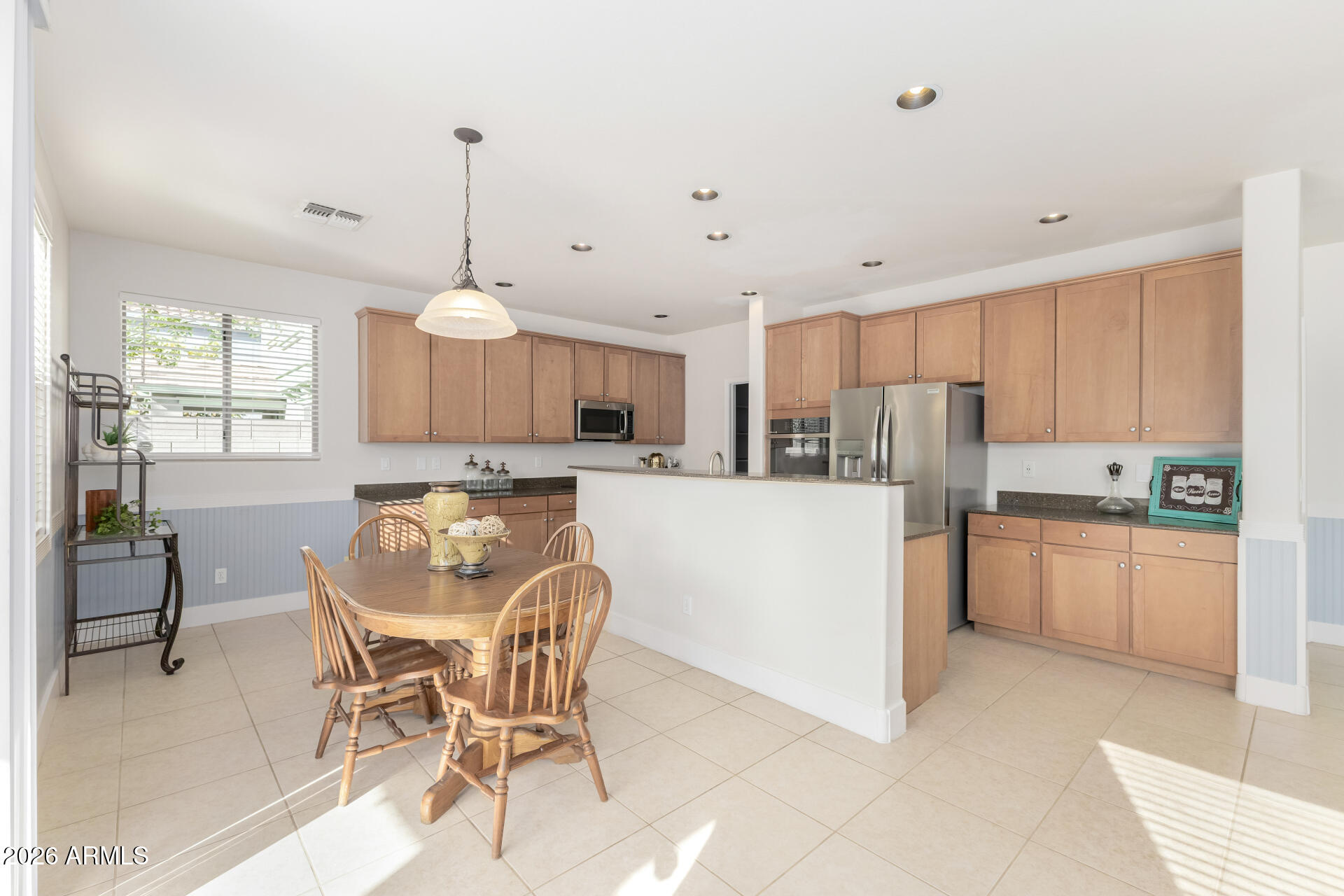 3535 East Terrace Avenue Gilbert, AZ 85234 - Photo 12 of 56 a kitchen with stainless steel appliances kitchen island granite countertop a table chairs and a refrigerator
