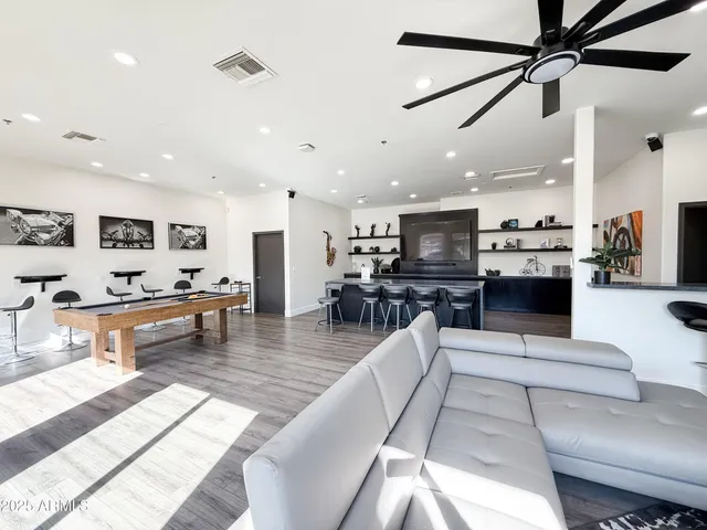 a living room with furniture kitchen view and a wooden floor