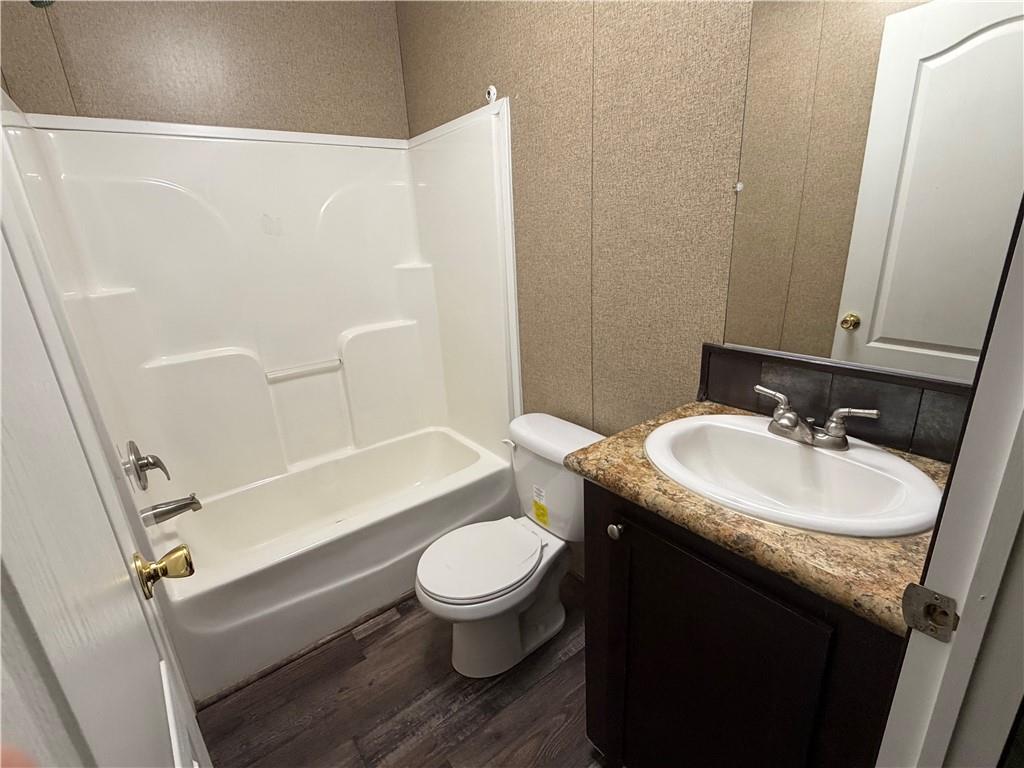 158 Kite Road Pittsview, AL 36871 - Photo 24 of 32 Bathroom featuring a white bathtub/shower combination, a white toilet, a vanity with a white basin sink, a granite-look countertop, and wood-finish flooring