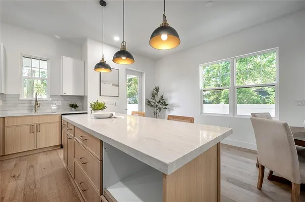 a kitchen with stainless steel appliances kitchen island granite countertop a dining table chairs and sink