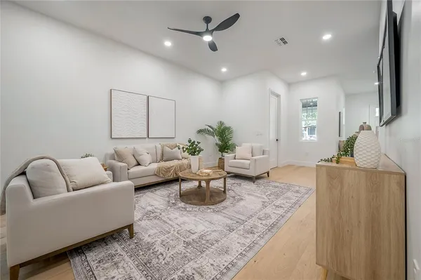 a living room with furniture a large window and wooden floor