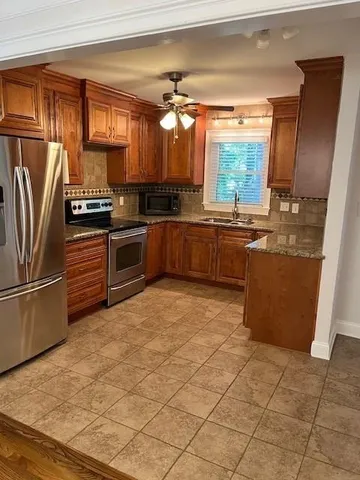a kitchen with stainless steel appliances granite countertop a refrigerator a stove and a sink