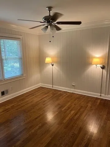 a view of an empty room with a window and wooden floor