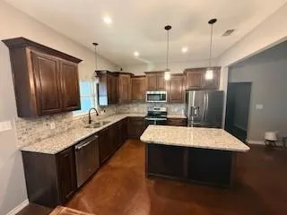 a large kitchen with kitchen island a large counter top space appliances and cabinets