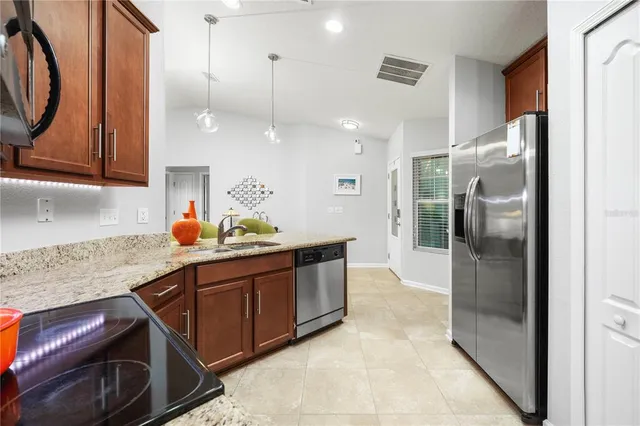 a kitchen with stainless steel appliances granite countertop a sink and a refrigerator