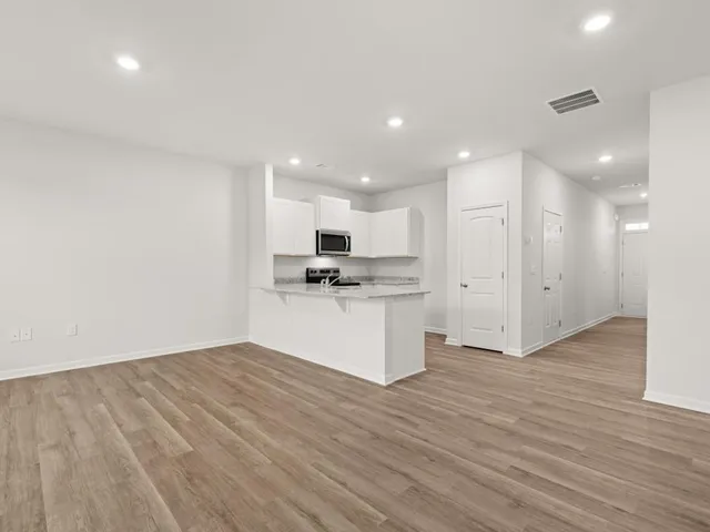 a view of kitchen with kitchen island wooden floor center island and stainless steel appliances