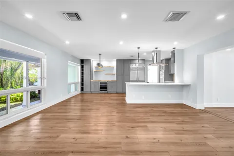 a view of a kitchen with kitchen island wooden floor and stainless steel appliances