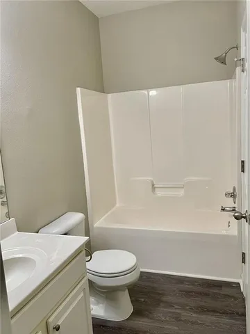 a bathroom with a toilet a sink and wooden floor