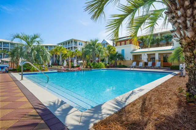 a view of swimming pool with a yard and palm trees