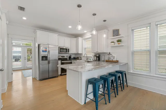 a kitchen with stainless steel appliances granite countertop a refrigerator a sink dishwasher a stove and a refrigerator with wooden floor