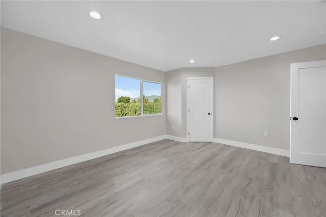 a view of an empty room with wooden floor and window