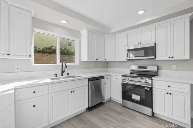 a kitchen with white cabinets appliances and a sink