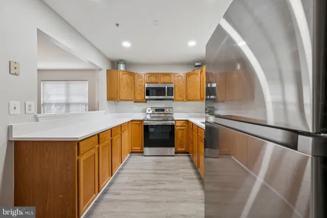a kitchen with stainless steel appliances a refrigerator a sink a stove top oven a counter space and cabinets