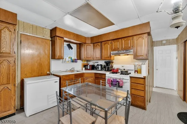 a kitchen with a refrigerator a stove a sink dishwasher and wooden cabinets with wooden floor