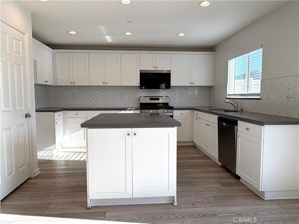 7631 Rubyred Gln Drive Riverside, CA 92507 - Photo 4 of 17 a kitchen with stainless steel appliances a stove top oven a sink a refrigerator and cabinets