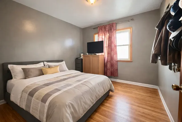 a bedroom with a bed and flat tv screen on the dresser