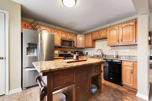 a kitchen with kitchen island granite countertop a sink appliances cabinets and furniture
