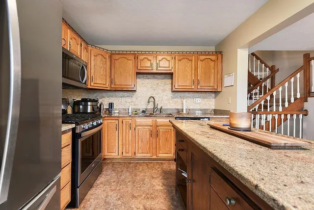 a kitchen with stainless steel appliances granite countertop a stove a sink and a refrigerator