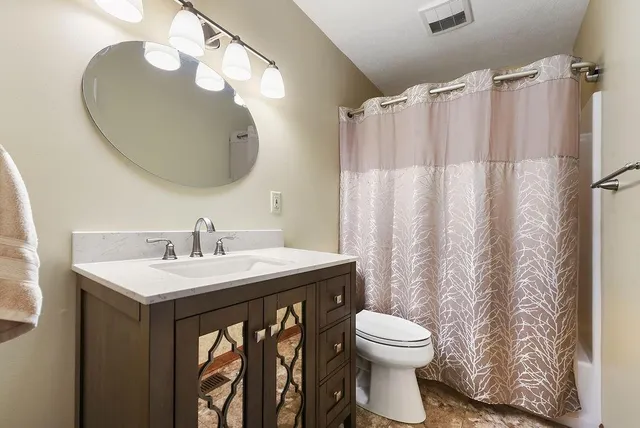 a bathroom with a granite countertop toilet a sink and a mirror