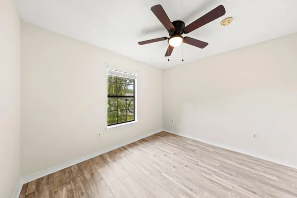 an empty room with wooden floor and ceiling fan