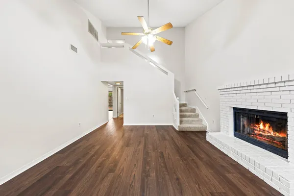 a view of an empty room with wooden floor fireplace and a window