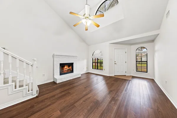 a view of an empty room with a window and wooden floor