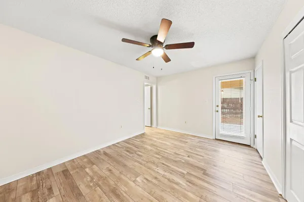 a view of empty room with wooden floor and ceiling fan
