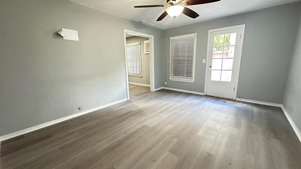 325 North Federal Highway, Unit 2 Lake Worth Beach, FL 33460 - Photo 2 of 10 an empty room with wooden floor chandelier fan and windows