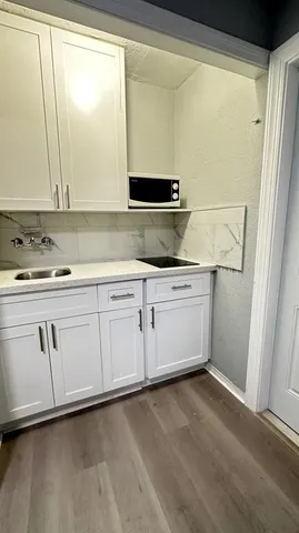 a kitchen with white cabinets and sink