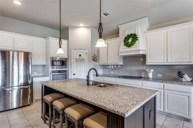 a kitchen with granite countertop kitchen island a sink stove and refrigerator