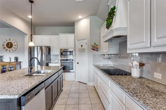 a kitchen with stainless steel appliances granite countertop a sink a stove and a refrigerator