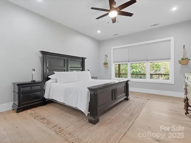 a large bed in a spacious bedroom next to a window and a chandelier