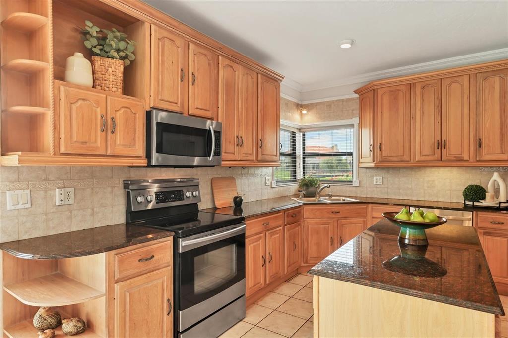 133 Inlets Boulevard, Unit 133 Nokomis, FL 34275 - Photo 13 of 63 a kitchen with stainless steel appliances granite countertop a sink stove and microwave