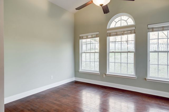 an empty room with wooden floor windows and closet