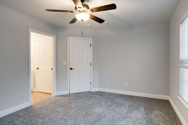 an empty room with closet and a chandelier fan
