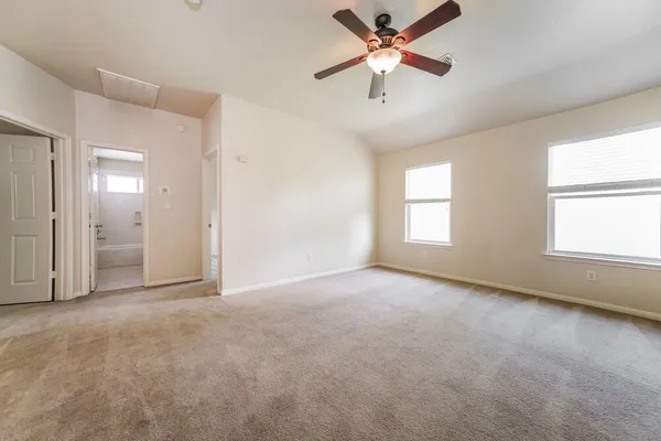 an empty room with chandelier fan and windows