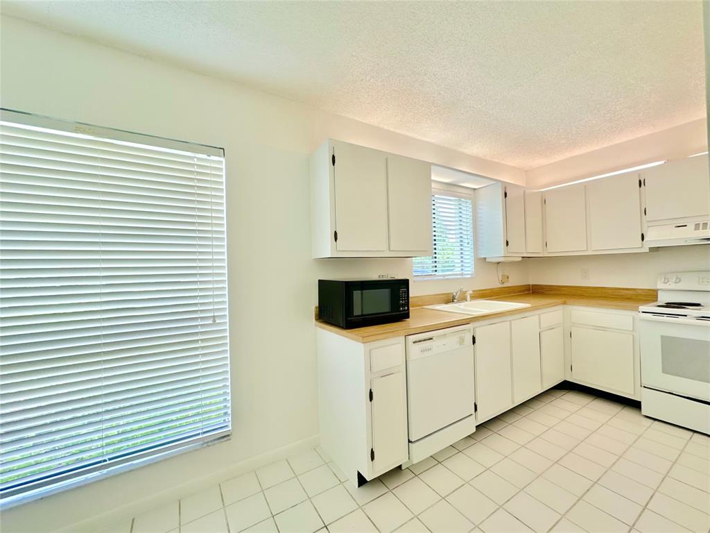 159 Northwest 70th Street, Unit 517 Boca Raton, FL 33487 - Photo 14 of 30 a kitchen with white cabinets and white appliances