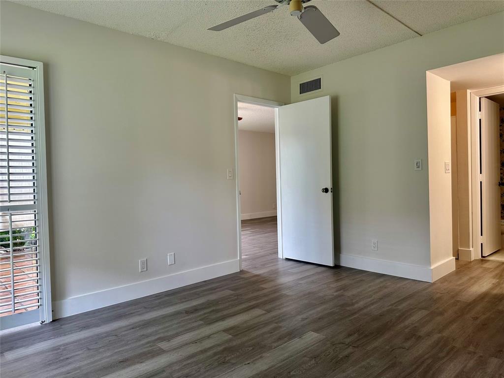 159 Northwest 70th Street, Unit 517 Boca Raton, FL 33487 - Photo 18 of 30 an empty room with wooden floor and a ceiling fan