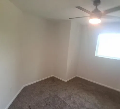 an empty room with a ceiling fan and carpet