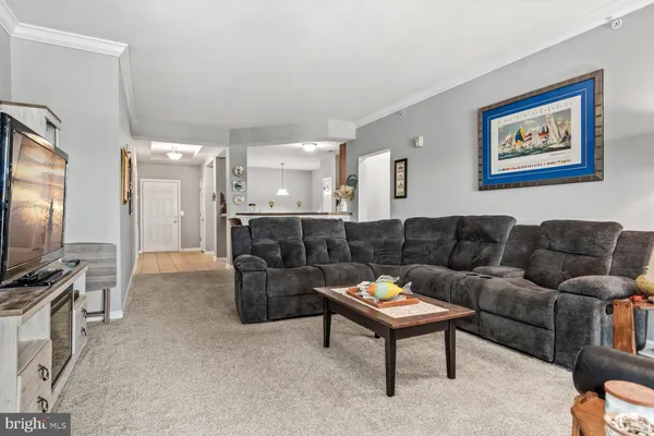 a living room with furniture a flat screen tv and a refrigerator