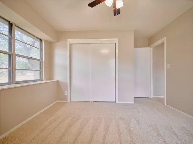 an empty room with ceiling fan and windows