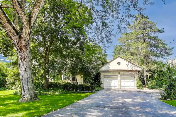 a front view of a house with a garden and trees