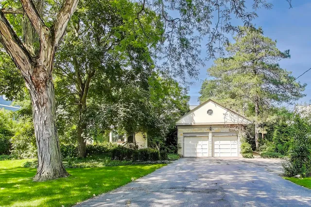 a front view of a house with a garden and trees