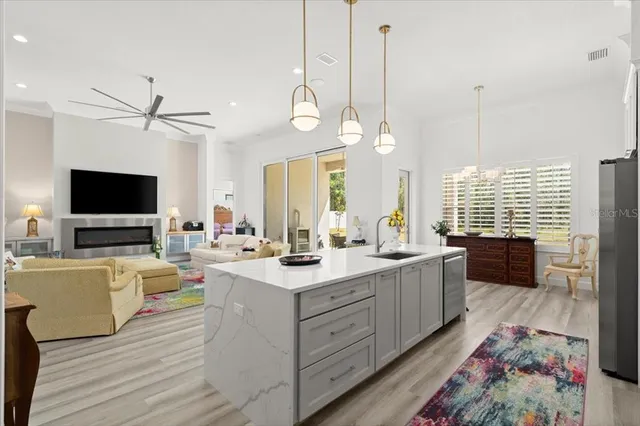 a large kitchen with kitchen island a stove a sink a center island and wooden floor