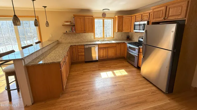 a kitchen with stainless steel appliances a refrigerator a sink a stove a microwave and wooden floors