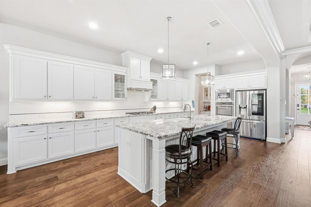 529 Prairie Run Aledo, TX 76008 - Photo 13 of 40 a kitchen with stainless steel appliances granite countertop a stove a sink a refrigerator and white cabinets with wooden floor