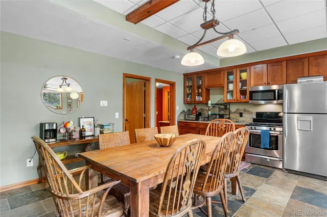 a dining room with stainless steel appliances a table chairs and chandelier