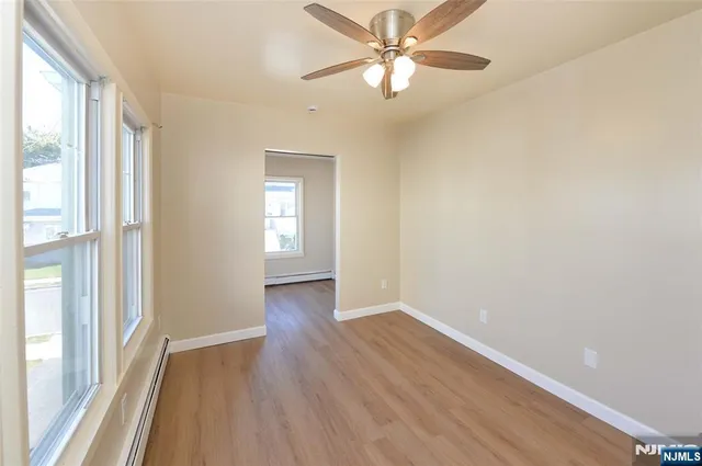 an empty room with wooden floor fan and windows